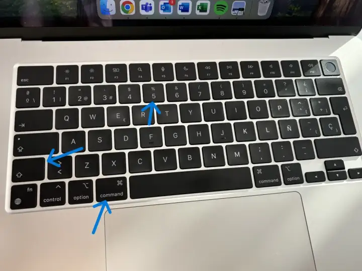 Aprende como hacer una captura de pantalla en el ordenador. Las flechas señalan las teclas Command, Shift y 5.